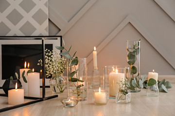 Beautiful burning candles and floral decor on table
