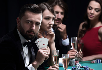 Poker player to four aces over dark background