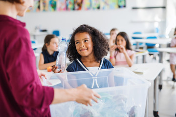 A teacher with small school kids in classroom learning about waste separation.