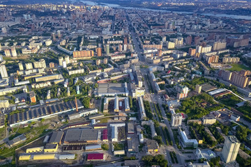 Panoramic aerial view of the city with tall buildings and a shopping center in the middle in Novosibirsk on a sunny afternoon at sunset. Industry and construction.