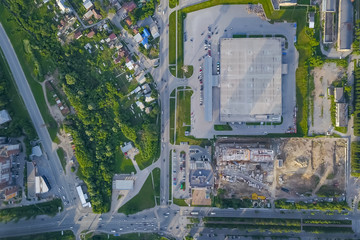 Panoramic aerial view of a large shopping center with parking where there are many cars in Novosibirsk on a summer afternoon at sunset. Industry and construction.