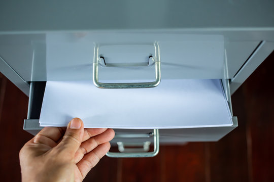 Woman's hand pick up white papers for write letter, Filing cabinet with open drawer, Silver grey metal colour, Administration and storage, Close up shot, Selective focus, Stationery, Business concept
