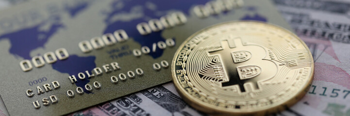 Gold coin bitcoin closeup lie on table with dollar paper and credit card aganist table background. Cryptocurrency exchange concept.