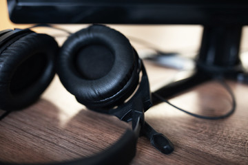 Obraz na płótnie Canvas black headphones with a microphone on a wooden table near a computer. Workplace