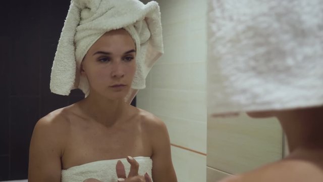 Young woman applying foundation cream after morning shower.