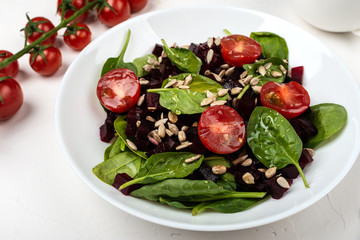 Healthy vegetarian food. Salad with beetroot, spinach, cherry tomatoes and seeds.