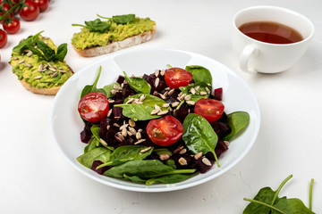 Healthy vegetarian food. Salad with beetroot, spinach, cherry tomatoes and seeds.