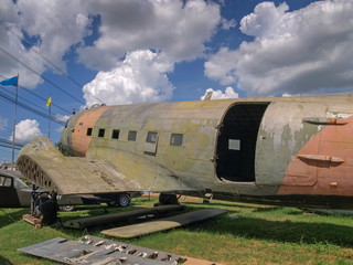 Old vintage military plane crash parking on grass field with blue sky background.