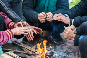 Fototapeta premium Hands of rural minority people warming up around the fire during the cold weather days in mountaious region in Vietnam