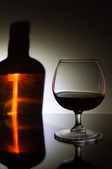 A glass on the table, in the reflection of the bottle.