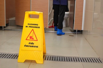 A yellow sign on the floor in the bathroom indicates that the symbol is being cleaned