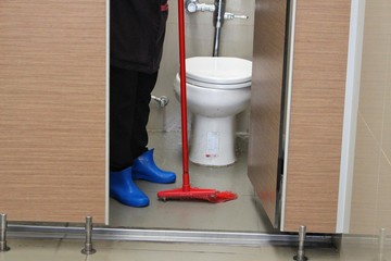 The housekeeper is cleaning the bathroom with a mop plot