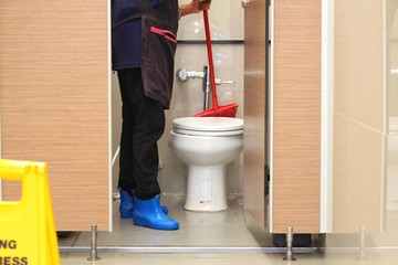 The housekeeper is cleaning the bathroom with a mop plot