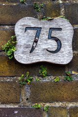 Numer 75 on an old brick wall with a key lying on top of the sign