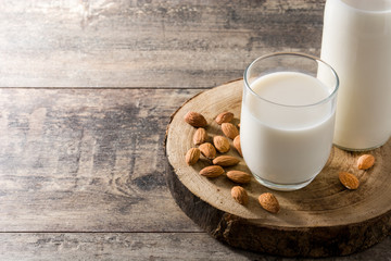 Almond milk in glass and bottle on wooden table. Copyspace