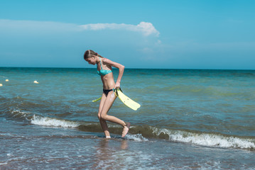 Teen girl with flippers in hands on the sea, ocean. Summer outdoor activities during the holidays.