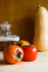 persimmons colored stil life, on a rustic home background, autumnal fruit concept, lot of negative space to add a text.