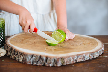 Shot of the preparation of a green detox juice. Woman cutting ingredients.