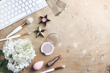 Women's blog concept. Office table with flowers, make up brush and cosmetics.