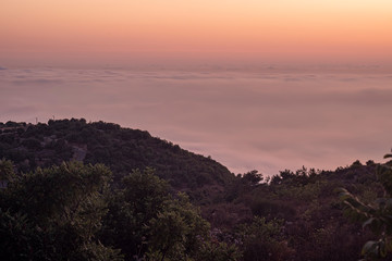 Beautiful colorful sunset over the mountain range and pine tree forest. Nature landscape. fogy sky with some orange reflections.