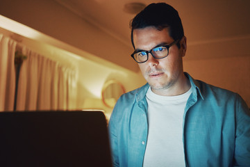 Concentrating man using laptop till late at night at home