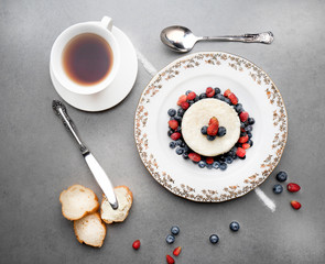 Delicious rice pudding with fresh berries and tea on a grey stone table