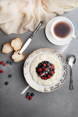 Delicious rice pudding with fresh berries and tea on a grey stone table