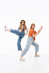 Portrait of two caucasian girls wearing casual clothes screaming and doing karate gestures