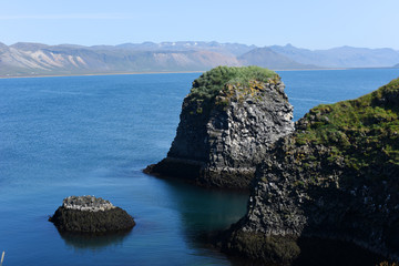 Naklejka premium West coast sea cliffs of Snaefellsnes Peninsula on Iceland.Pure blue water with high cliffs above sea. Beautiful colourful scenic view of basalt rock reef.