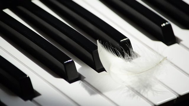 Close-up piano keyboard and flying away white feather. Concept of creativity and inspiration