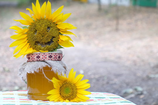 organic honey in glass jar, smiling funny sunflower and bee on natural background, healthy lifestyle, apiculture, healthy products and food, beekeeping, rustic background