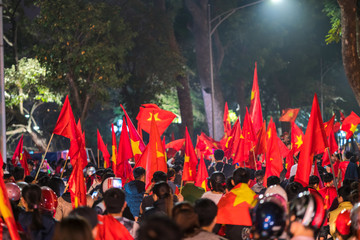 Blurred background of crowd of Vietnamese football fans down the street to celebrate the win after soccer, with a lot of Vietnamese flags raising high