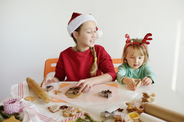 Two cute girls making cookies for Christmas. Children bake ginger biscuits.