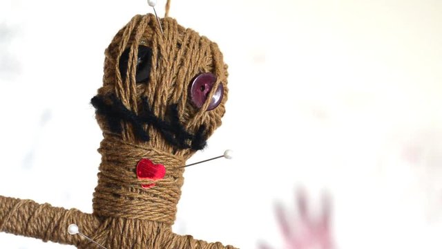 Close-up voodoo doll turns round slowly on white background. Ancient occult thing
