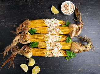 Baked corn cobs in a spicy sauce with lime on a dark background