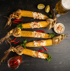 Baked corn cobs in a spicy sauce with lime on a dark background