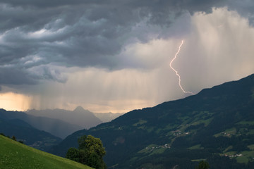 Dramatic sky with thunderstorm and lightning bolt in the mountains at sunset