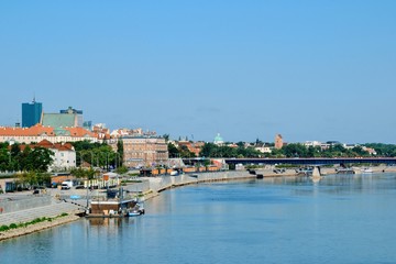 Fototapeta na wymiar Summer cityscape, view from Swietokrzyski Bridge to Vistula river, the Vistula Boulevards promenade and Old Town. Warsaw, Poland