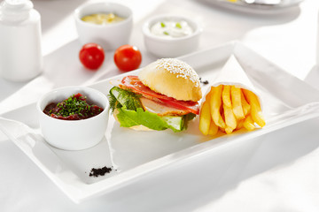 Gourmet, restaurant, delicious dinner food - close up of Sandwich with Smoked Meat, Tomato and Cucumber. Garnished with French Fries and Vegetables Sauce