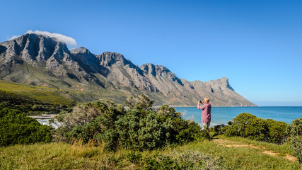 Woamn taking holiday photograph of Kogelberg nature reserve mountains South Africa with phone camera.