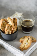 Biscotti in a bowl on a wooden tray with coffee