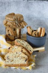Biscotti in a bowl and a glass jar with a napkin on a concrete background