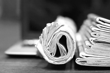 Newspapers and laptop. Pile of daily papers with news on the computer. Pages with headlines,...