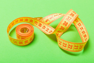 Close up of tangled measuring tape on green background. Fitness and healthy diet concep with...