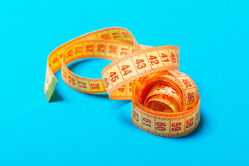 Perspective view of spiral measuring tape on blue background. Close up of slimming concept