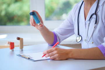 Doctor writes prescription for asthma inhaler to asthmatic patient during medical consultation and...