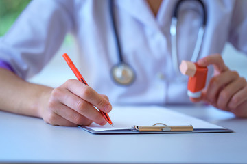 Nurse writes medical prescription for asthma inhaler to asthmatic patient during medical...