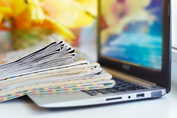 Newspapers and Laptop. Magazines Stacked on Computer. Tabloid Journals and Open Notebook -...