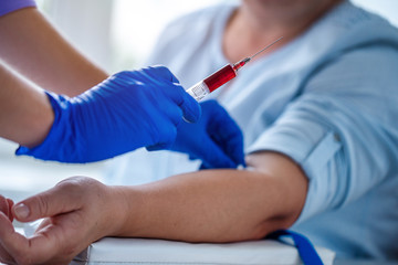 Nurse in rubber blue medical gloves takes blood from a vein for laboratory test.