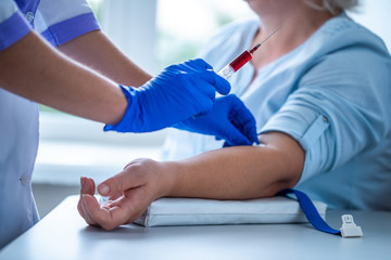 Nurse in rubber blue medical gloves takes blood from a vein for laboratory test.